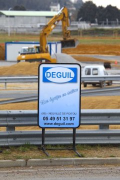 Panneau d'affichage représentant une société de travaux devant un chantier.